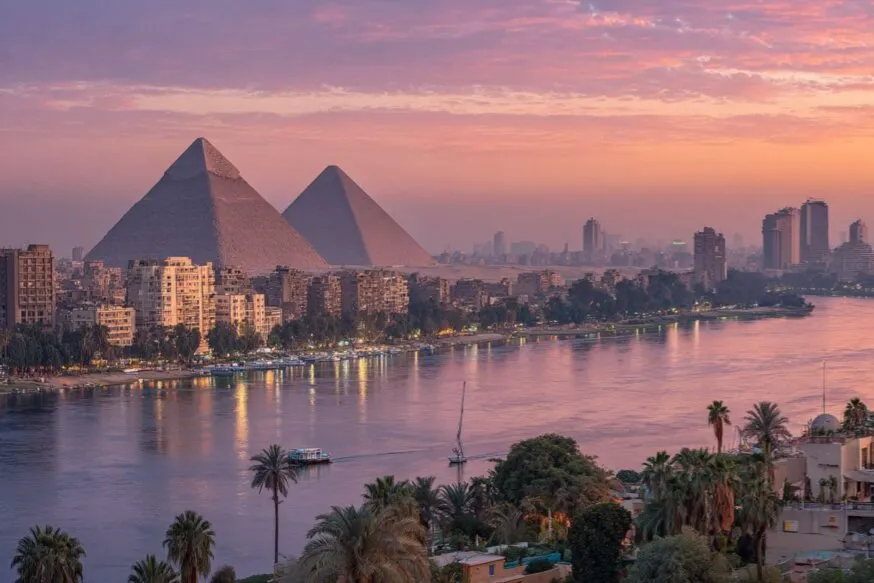 The Pyramids of Giza above Cairo's skyline and the Nile at dusk