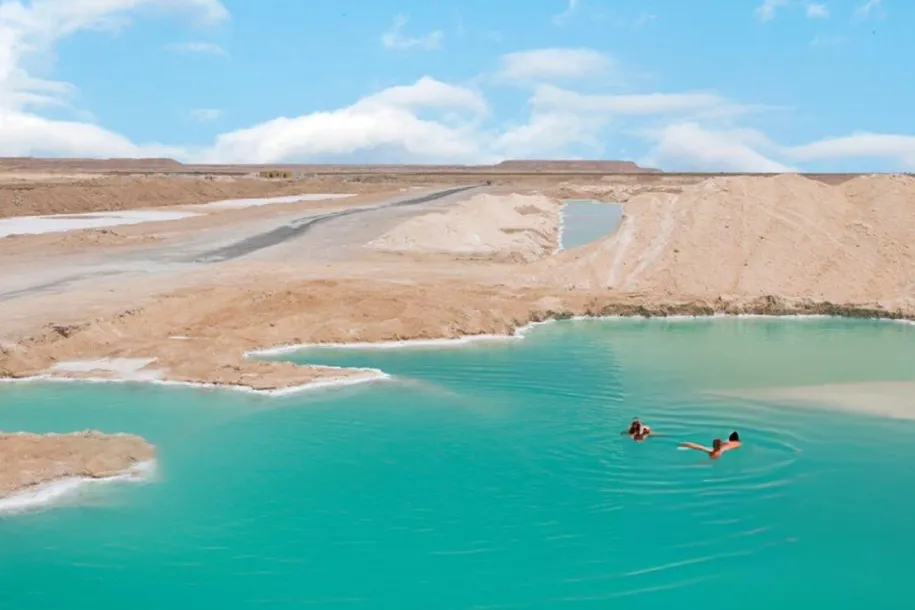 A turquoise salt lake among pale dunes near Siwa Oasis