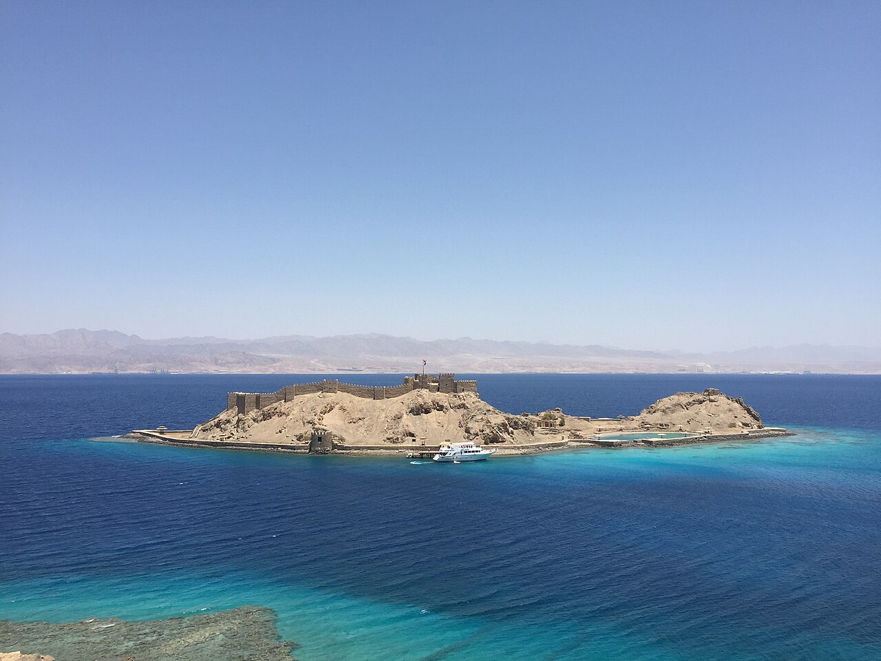 Pharaoh's Island in the Gulf of Aqaba, its walls and Salah El Din Castle above turquoise reef water