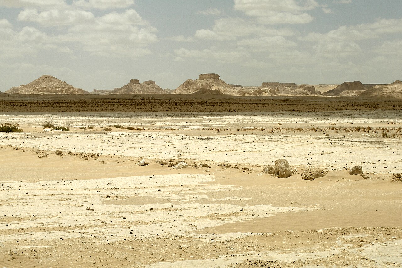 A white chalk plain in the Farafra depression, with flat-topped rock formations on the horizon