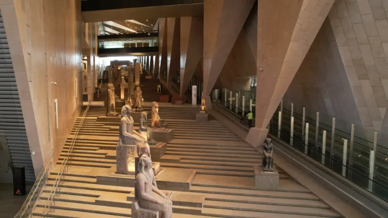 The Grand Staircase of the Grand Egyptian Museum, colossal statues lit along its steps