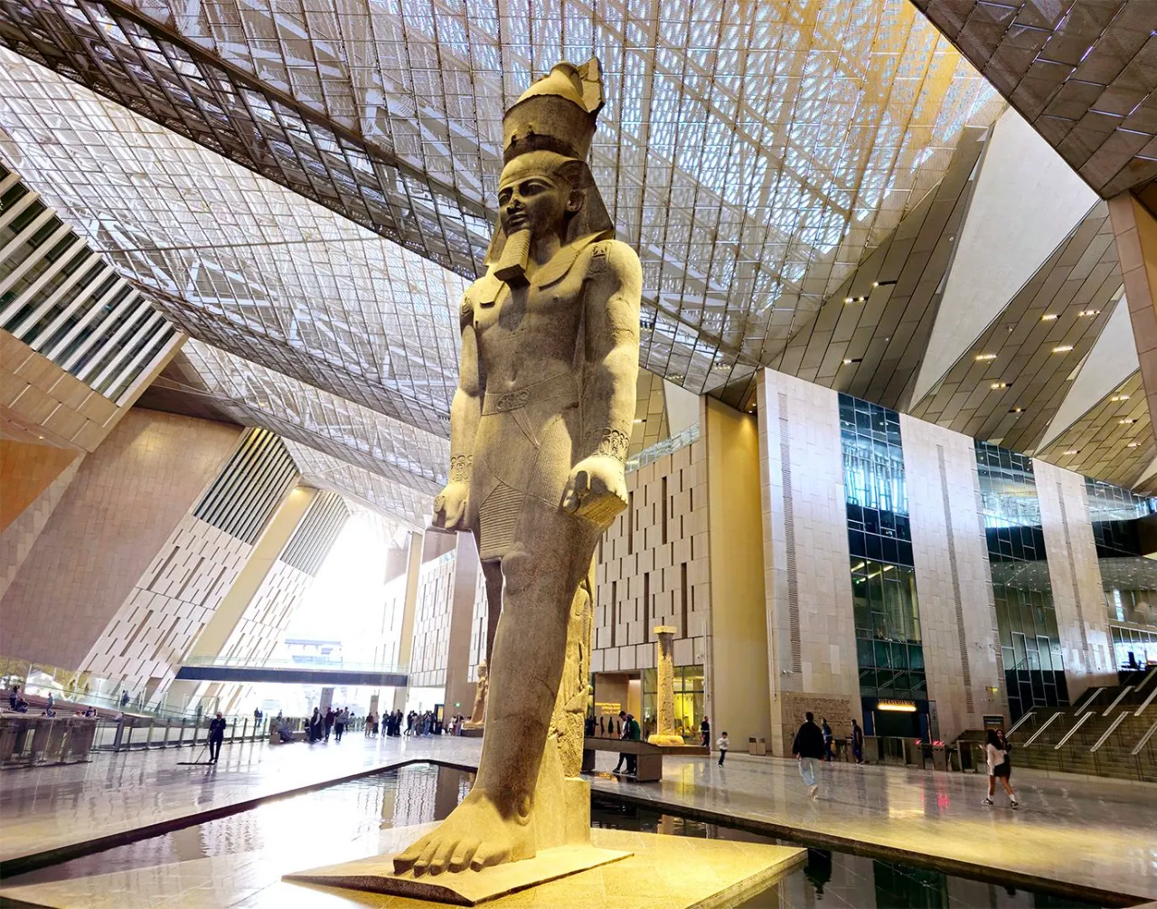 Looking up at the colossal statue of Ramesses II beneath the latticed roof of the museum atrium