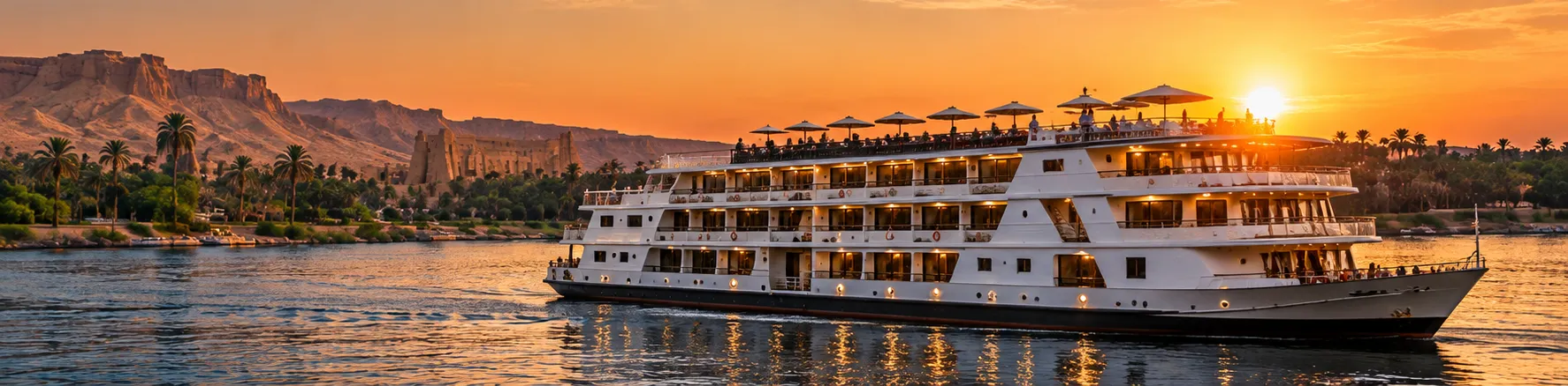 A five-star Nile cruise ship sailing at sunset past palms and a temple beneath the Theban hills