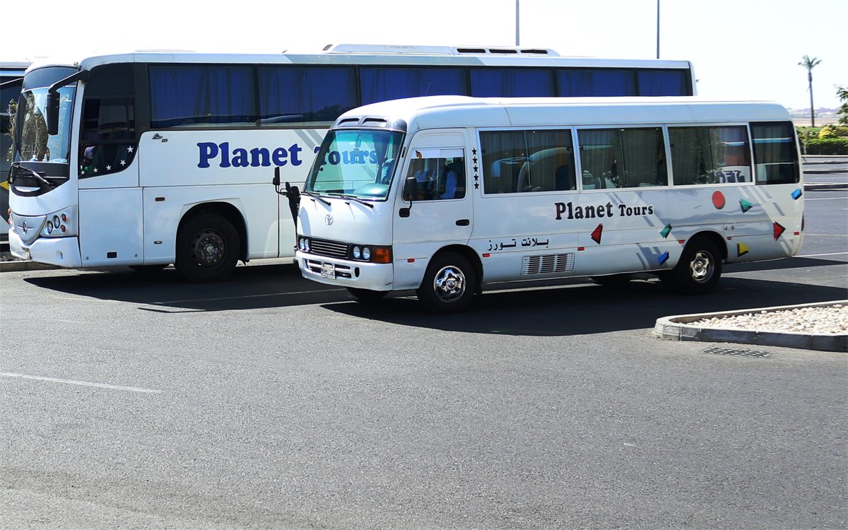 A Toyota Coaster minibus parked in front of a full-size coach