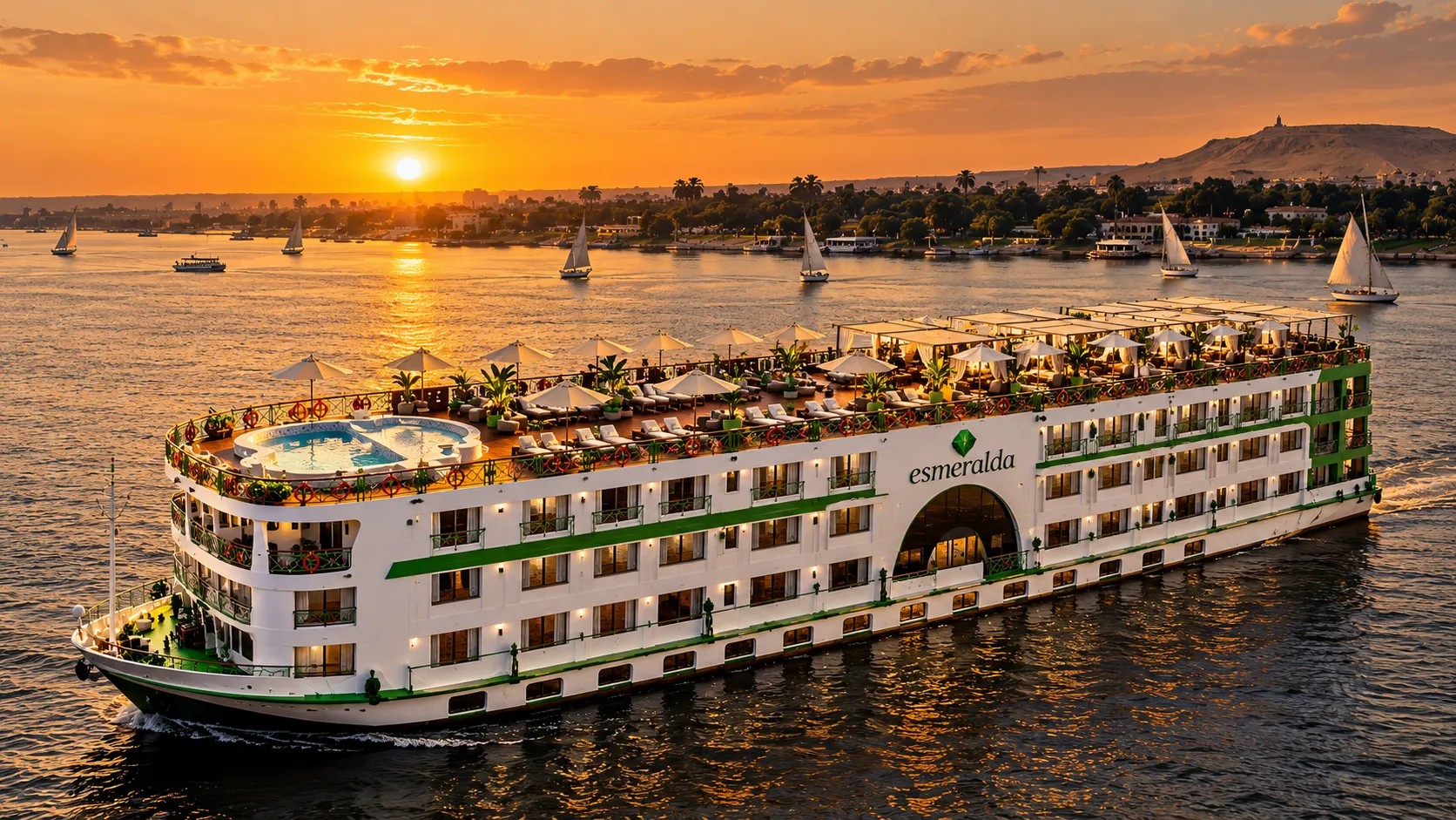 MS Esmeralda on the Nile at sunset, its sun deck set with loungers, parasols and a pool