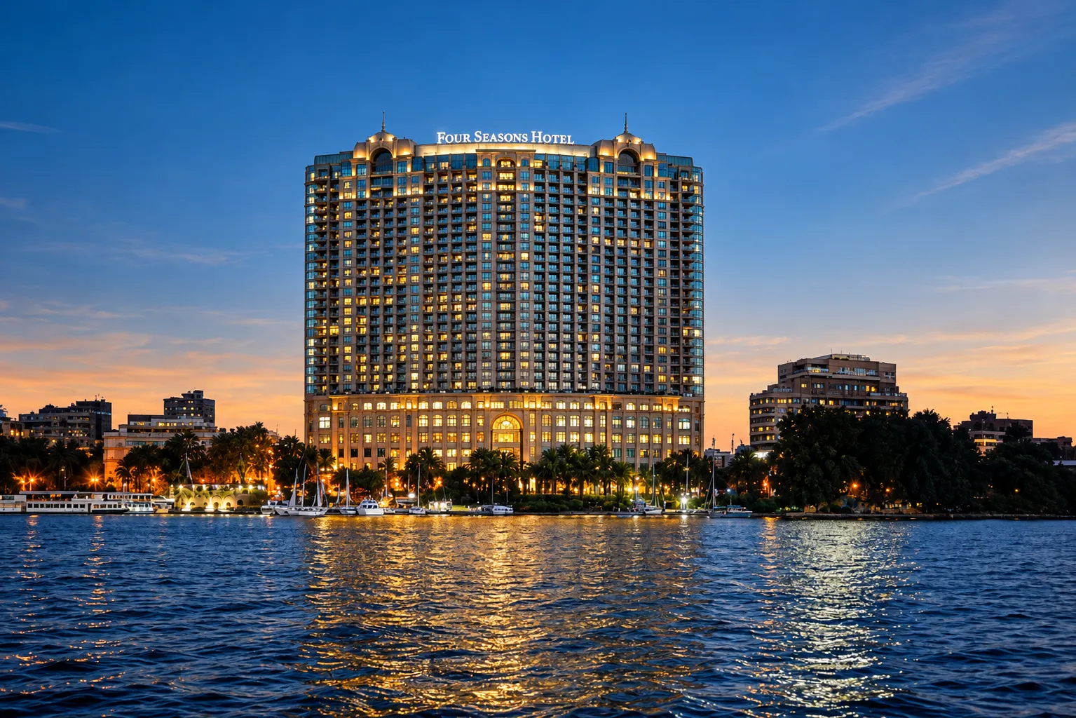 Four Seasons Hotel Cairo at Nile Plaza lit at dusk, its reflection on the Nile