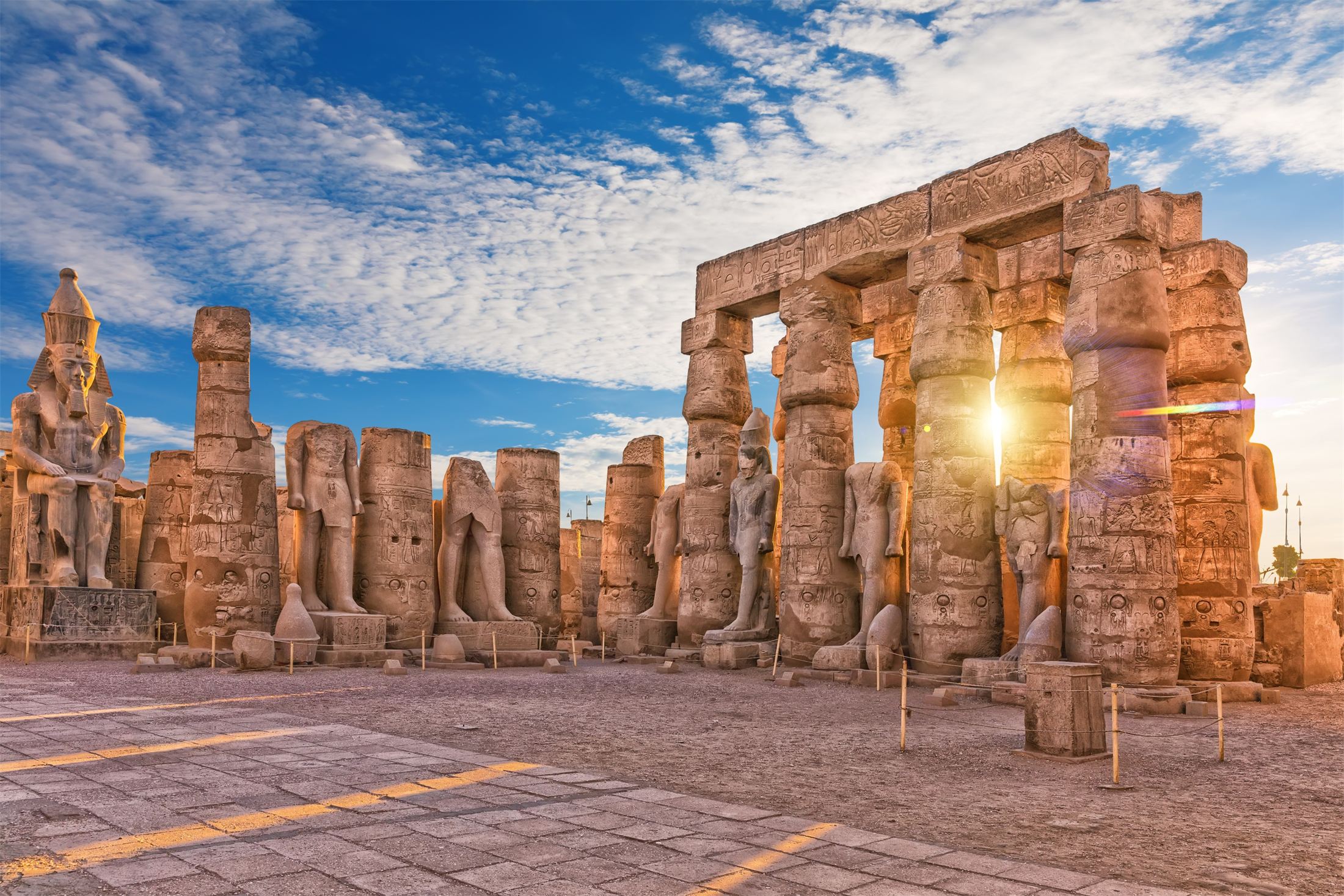 Colossal statues and papyrus columns of Luxor Temple in golden evening light
