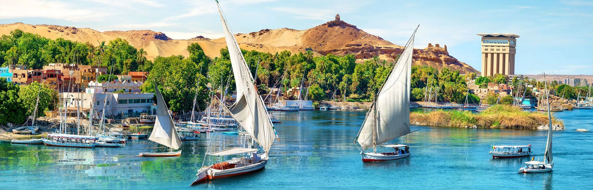 Feluccas moored along the Nile corniche at Aswan, with the desert hills beyond